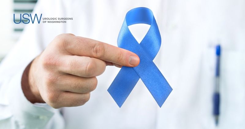 Urologist in white coat holds blue ribbon for prostate cancer awareness at Urologic Surgeons of Washington in DC.