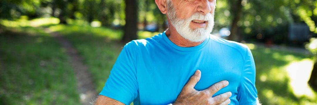 Man exercising outside gripping chest with one hand